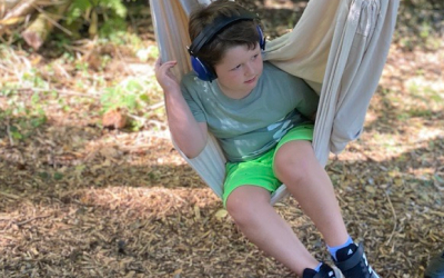 A little boy swinging in a hammock.